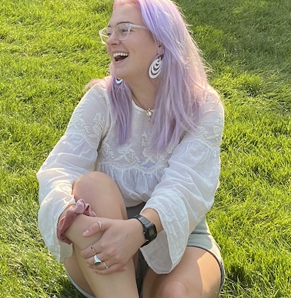 Sabina laughing while sitting in the grass