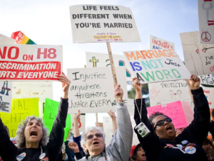 Women in community, shouting and holding signs about equality.